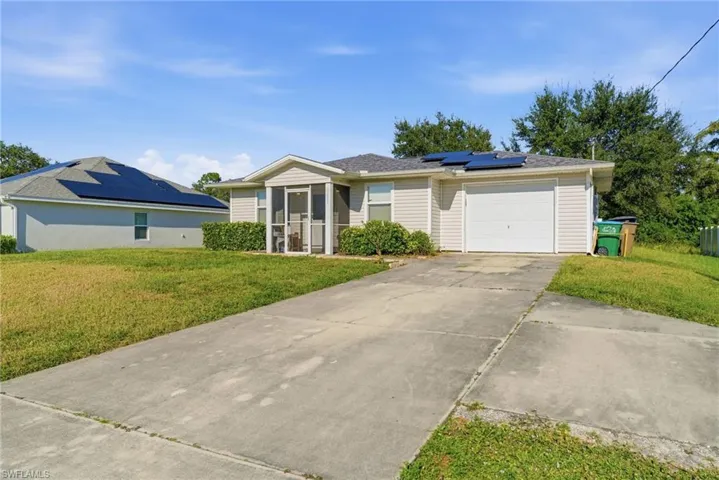 Ranch-style home with solar panels, a front lawn, driveway, a garage, and a sunroom