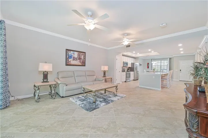 Expansive open-concept great room featuring volume ceilings, large-format tile flooring, and seamless flow to the kitchen, dining area, and screened lanai.