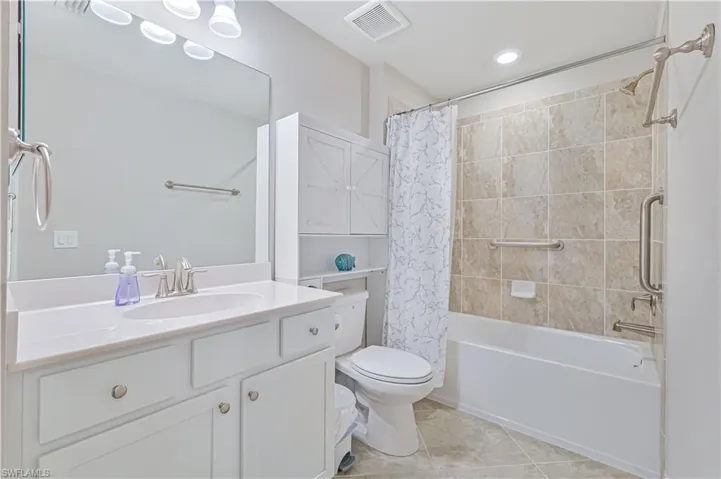 Well-appointed guest bathroom featuring a tiled tub/shower combination, spacious vanity, ample storage, and modern finishes throughout.