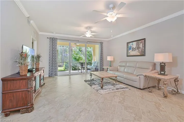 Spacious great room featuring volume ceilings, tile flooring, abundant natural light, and seamless access to the screened lanai overlooking the preserve.