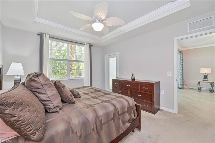 Spacious primary suite featuring a tray ceiling, large window with peaceful preserve views, plush carpeting, and a relaxing retreat-like atmosphere.