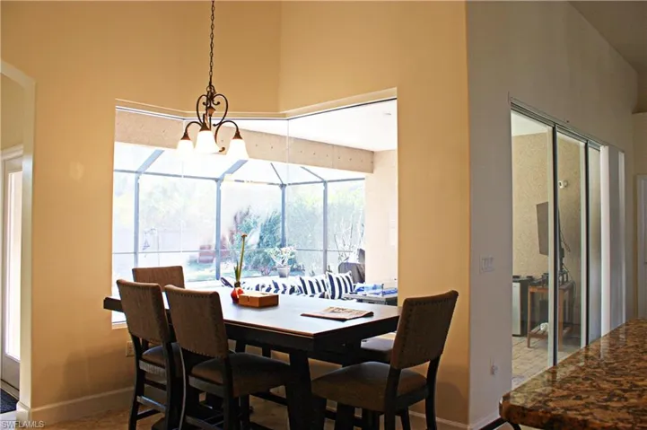 Bay window dining area with a wrought iron chandelier, overlooking a screened patio