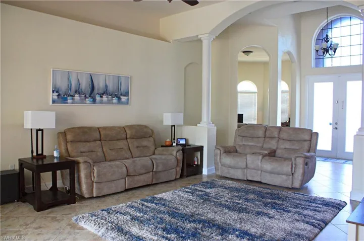 Living area featuring neutral-toned walls, tile flooring, and vaulted ceilings