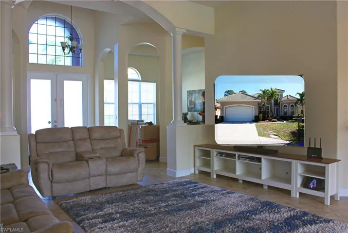 Spacious living area featuring double-door entry with transom window, tile flooring, and decorative arched doorways