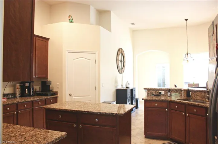 Kitchen featuring rich wood cabinetry, granite countertops, a central island, and tile flooring
