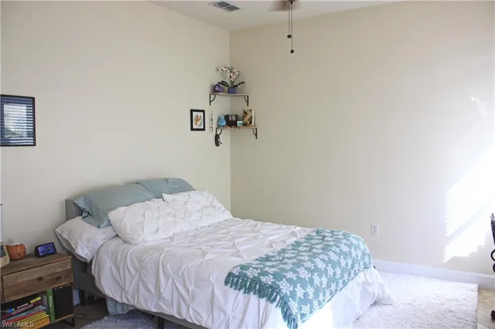 Bedroom featuring neutral wall tones, a ceiling fan, baseboard molding, and a corner wall shelf