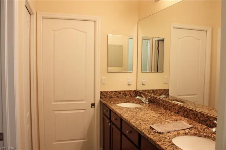 Dual vanity with an integrated countertop and undermount sinks, full-width mirror, and shaker-style cabinetry