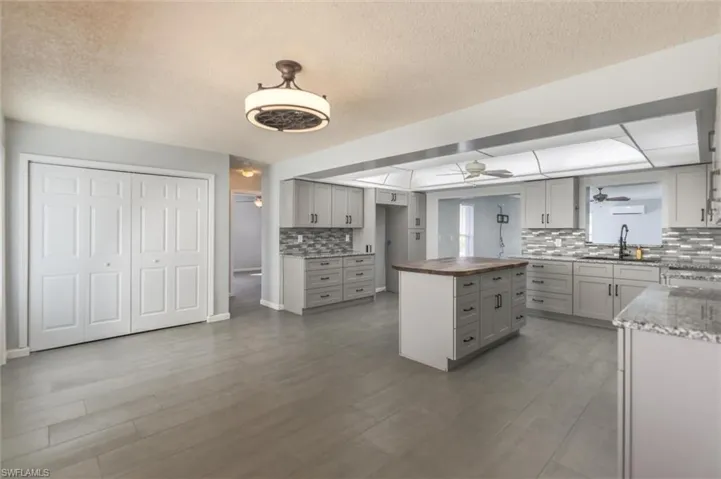 Kitchen with backsplash, gray cabinets, sink, and wooden counters