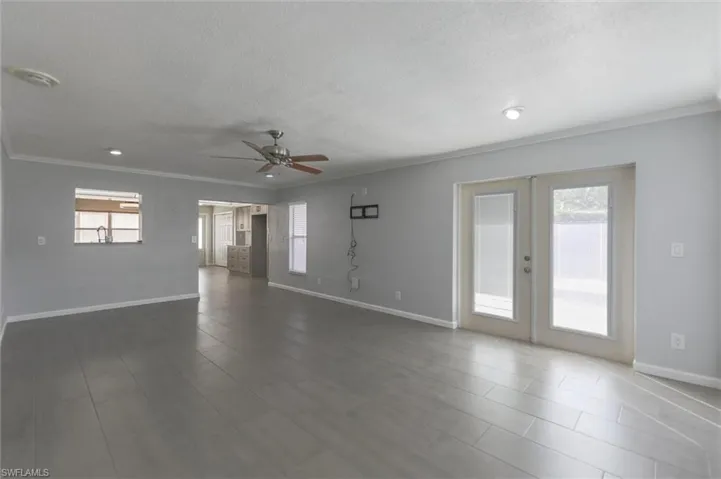 Unfurnished room with a textured ceiling, ornamental molding, ceiling fan, and french doors