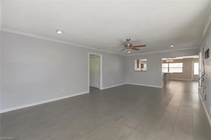 Spare room featuring dark hardwood / wood-style flooring, ceiling fan, and crown molding