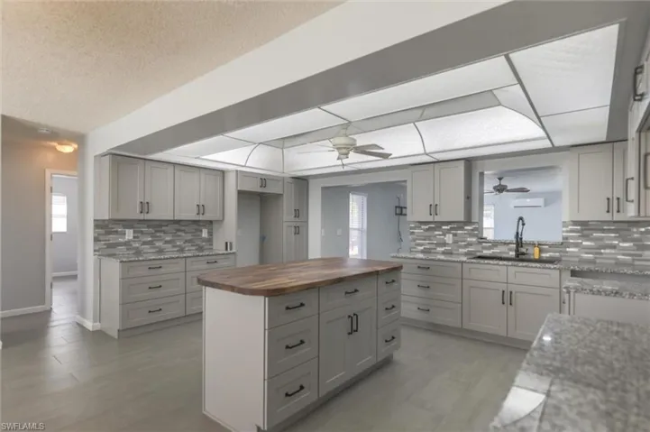Kitchen featuring decorative backsplash, sink, gray cabinets, and wood counters