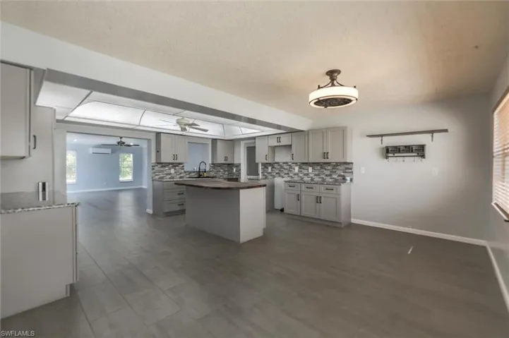Kitchen with dark hardwood / wood-style flooring, backsplash, gray cabinets, and ceiling fan