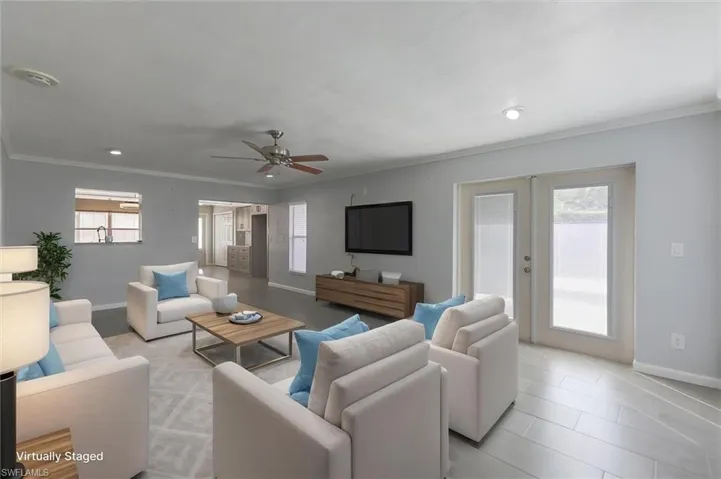 Virtually-staged tiled living room with french doors, ceiling fan, and ornamental molding