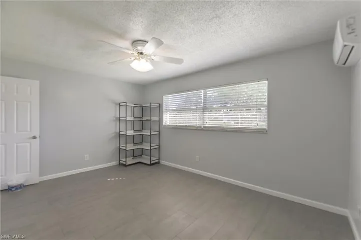 Spare room with hardwood / wood-style floors, ceiling fan, an AC wall unit, and a textured ceiling