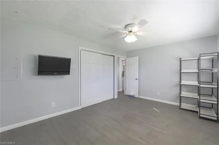 Unfurnished bedroom with ceiling fan, dark hardwood / wood-style flooring, and a textured ceiling