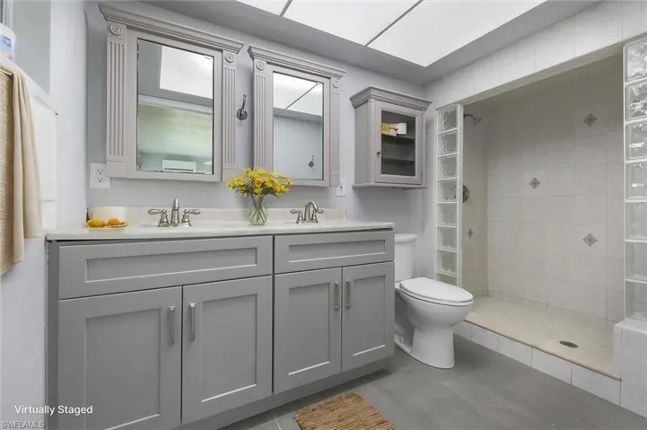 Bathroom with a tile shower, vanity, and toilet