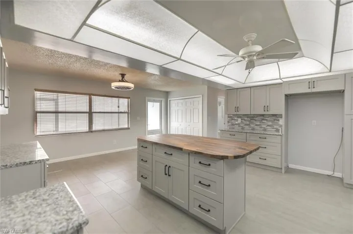 Kitchen featuring gray cabinetry, ceiling fan, butcher block countertops, backsplash, and light tile patterned flooring