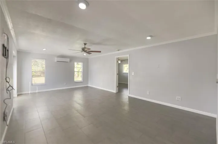Empty room featuring ornamental molding, ceiling fan, and a wall unit AC