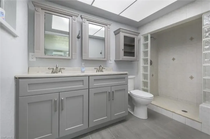 Bathroom with a tile shower, vanity, and toilet