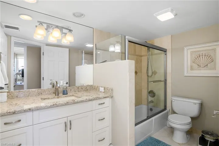 Full bathroom featuring vanity, tile patterned flooring, enclosed tub / shower combo, and toilet