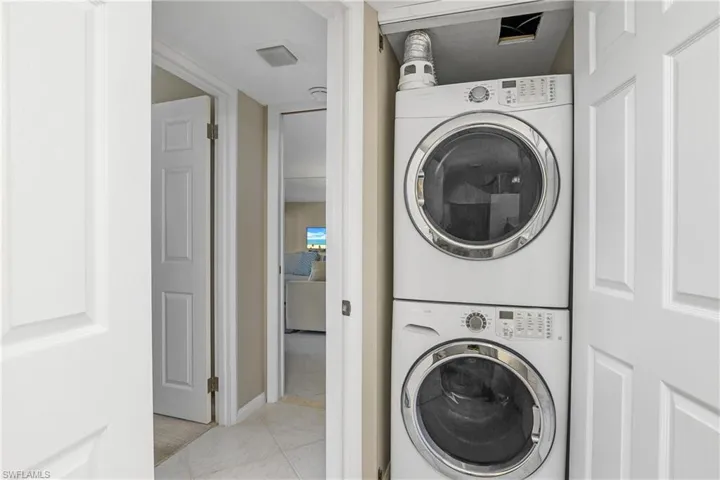Laundry area featuring stacked washer and clothes dryer and light tile patterned floors