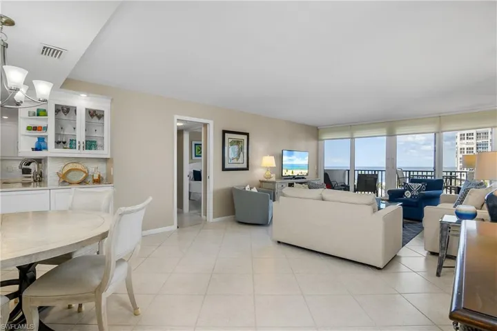 Living room featuring expansive windows, light tile patterned flooring, sink, and a notable chandelier