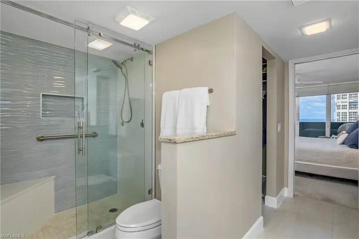 Bathroom with toilet, tile patterned flooring, and a shower with door