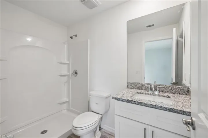 Bathroom with walk in shower, oversized vanity, and toilet