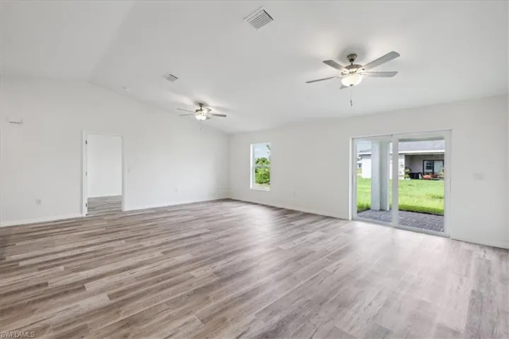Unfurnished room with ceiling fan, light hardwood / wood-style floors, and lofted ceiling