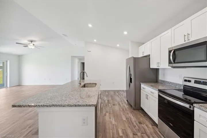 Kitchen featuring appliances with stainless steel finishes, light wood-type flooring, vaulted ceiling, and ceiling fan
