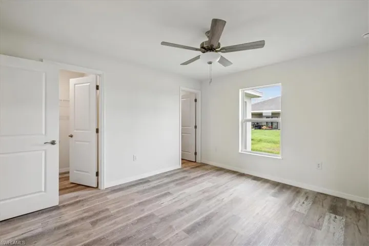 Unfurnished bedroom with ceiling fan, a walk in closet, and light hardwood / wood-style floors