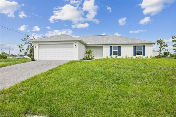 Ranch-style house with a garage and a front lawn
