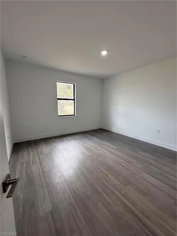 Unfurnished room featuring dark wood-type flooring and baseboards