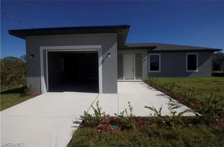 View of front of home with a garage, driveway, stucco siding, and a front yard