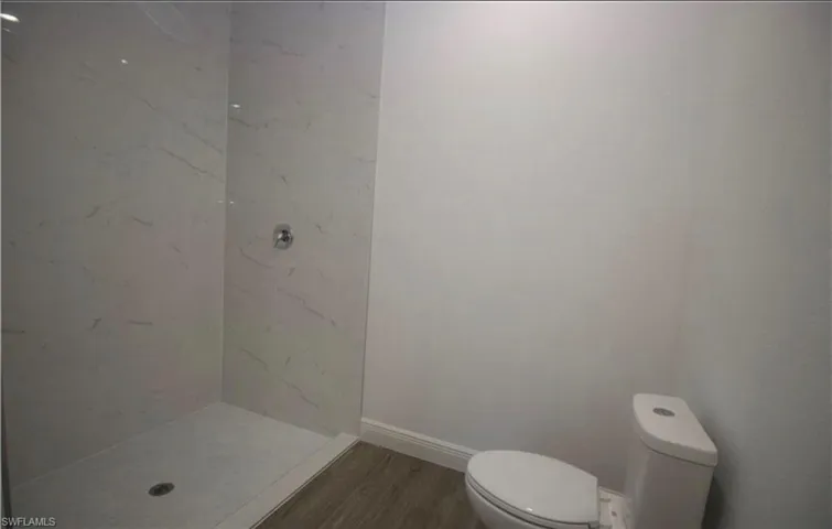 Bathroom featuring a marble finish shower and wood finished floors