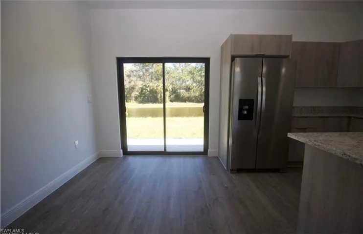 Unfurnished dining area with dark wood finished floors and baseboards