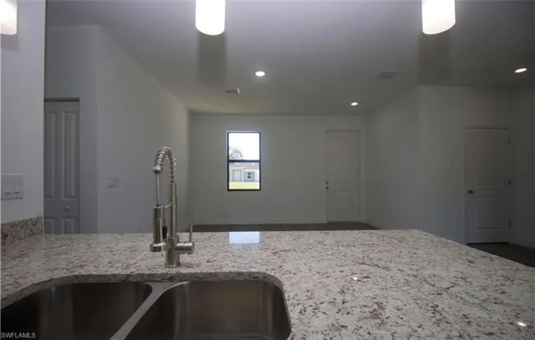 Kitchen featuring light stone counters, a peninsula, and recessed lighting