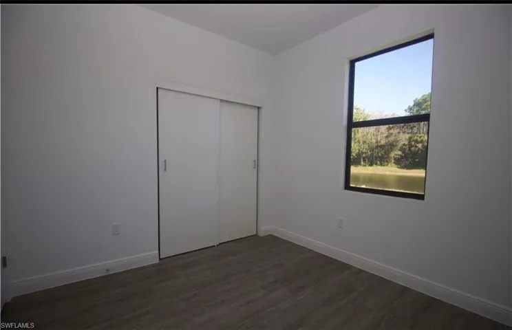 Unfurnished bedroom with dark wood-style floors and a closet