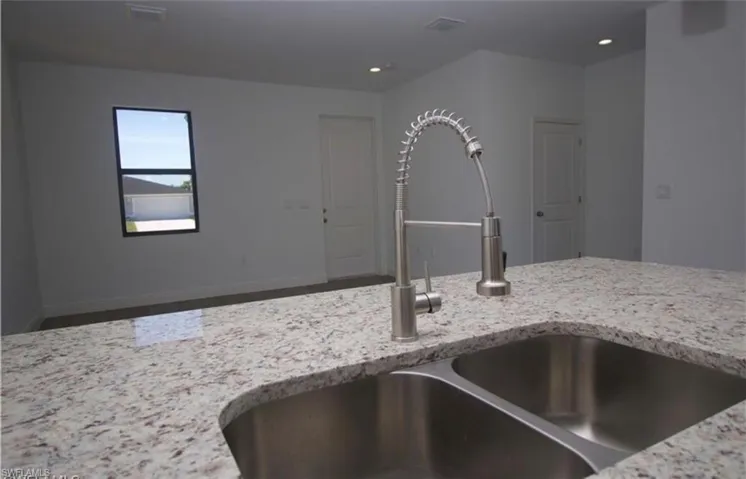 Kitchen with light stone countertops and recessed lighting