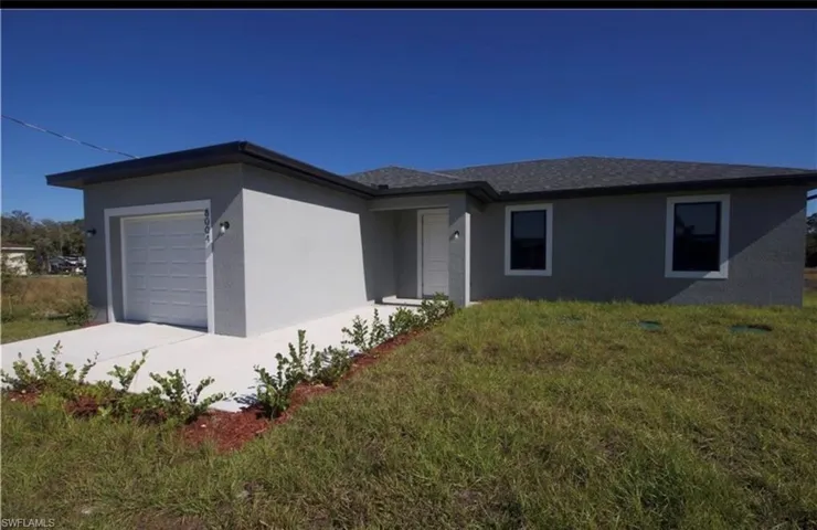 Ranch-style house featuring stucco siding, a garage, a front yard, and concrete driveway