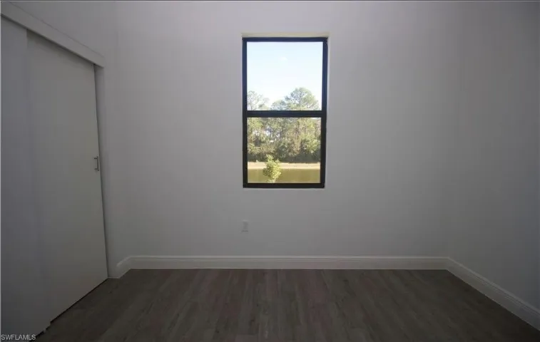Empty room featuring dark wood-style floors and baseboards