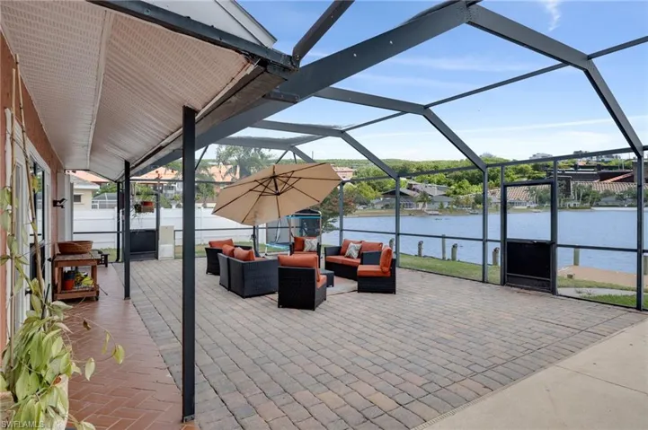 View of patio with a sunroom, a lanai, a water view, and an outdoor living space
