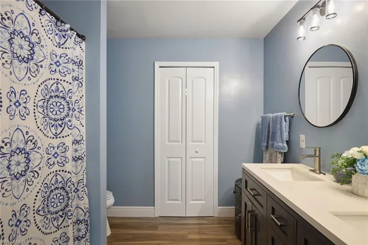 Bathroom featuring hardwood / wood-style floors, vanity, curtained shower, and toilet