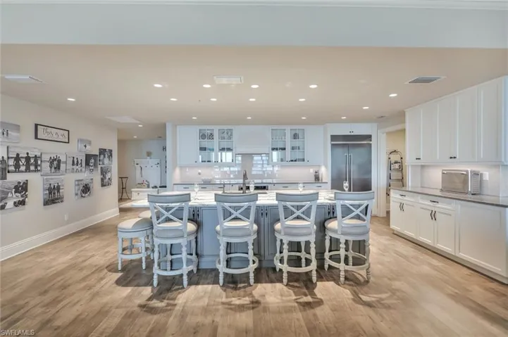 Two tone kitchen with a kitchen bar, a spacious island, built in fridge, light wood-style flooring, and dual tone cabinets