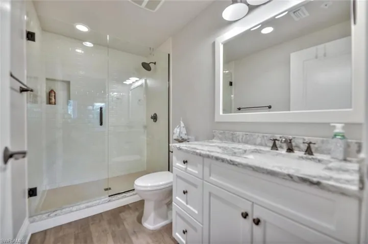 Bathroom featuring vanity, a stall shower, recessed lighting, and light wood-type flooring