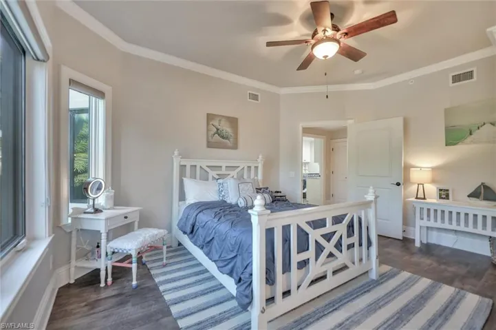 Bedroom featuring ornamental molding, dark wood-style flooring, and ceiling fan