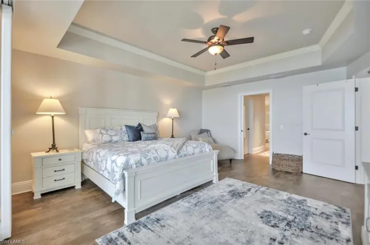 Bedroom with a tray ceiling, ornamental molding, a ceiling fan, and wood finished floors