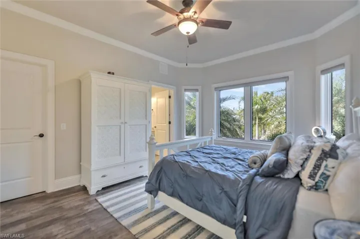 Bedroom with crown molding, wood finished floors, and a ceiling fan