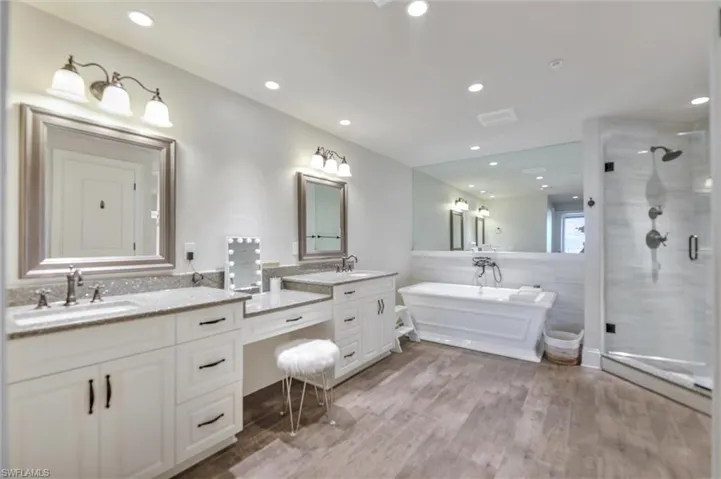 Full bath with double vanity, a stall shower, light wood-style floors, a tub to relax in, and recessed lighting