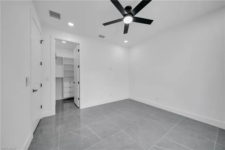 Unfurnished bedroom with a spacious closet, recessed lighting, and a ceiling fan